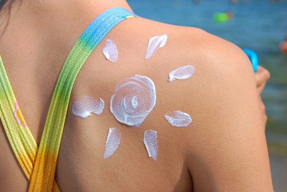 Acercamiento al hombro de una mujer en la playa con crema en forma de sol