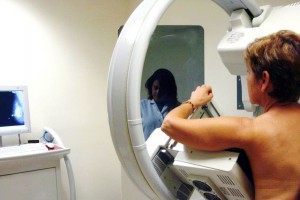 Mujer apoyando su cuerpo en un mastográfo