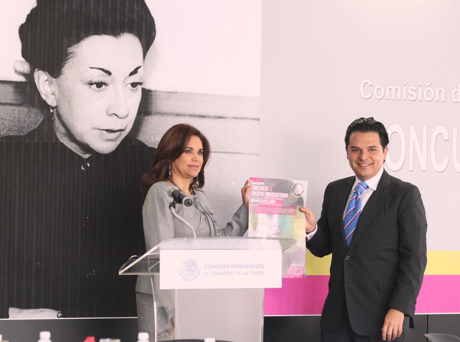 Blanca Alcalá y Zoé Robledo sosteniendo documento de convocatoria al fondo imaden de Rosario Castellanos