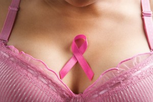 Acercamiento a una mujer usando brassier rosa con el listón rosa de cáncer de mama