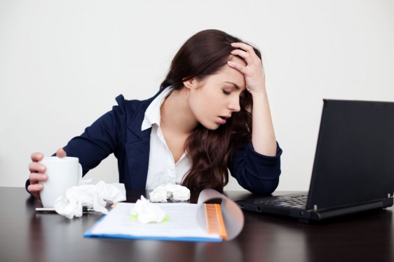 Mujer cansada sentada en odicina con una computadora