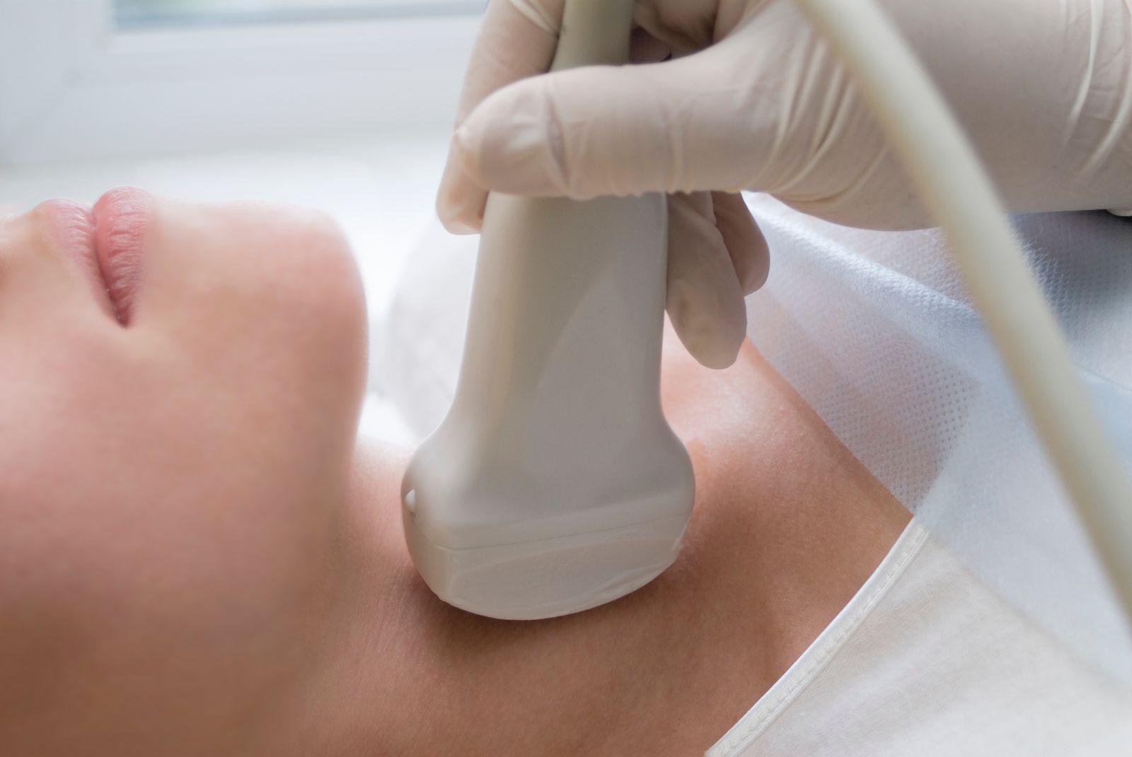 Exploración de ultrasonido en la tiroides de mujer