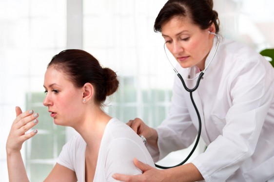 doctora esuchando con estetoscopi en la espalda de una mujer