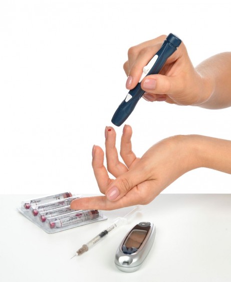 Acercamiento a las manos de una ujer que se mide la glucosa al lado insulina
