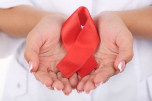 mujer con cinta roja en manos signo de conciencia del SIDA