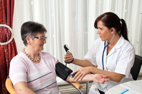 Doctora con bauometro midiendo presió arterial de mujer adulta mayor