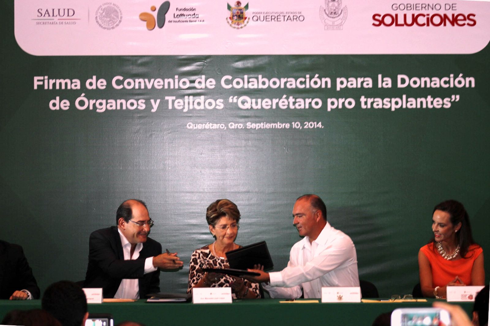 Jorge Lois Rodríguez, Mercedes Juan y José Eduardo Calzada Rovirosa sentados con otra persona firmando un documento