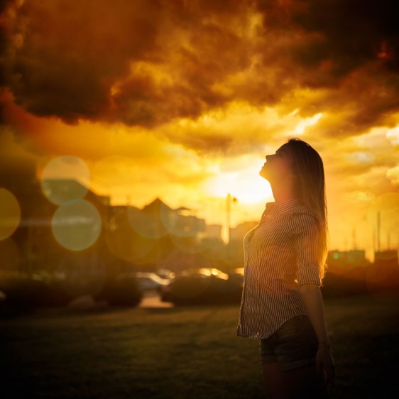 Mujer observando al ciel al fono un sol anaranjado