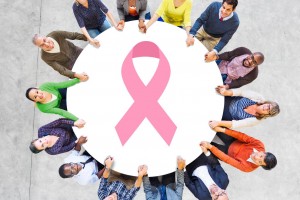 Mujeres alrededor de una malla de seguirdad circular con una ilustración del listón de cáncer de mama
