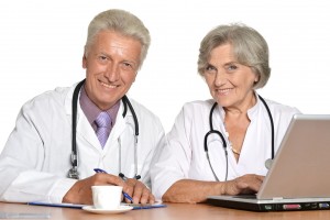 Par de médicos adultos mayores trabajando en una mesa