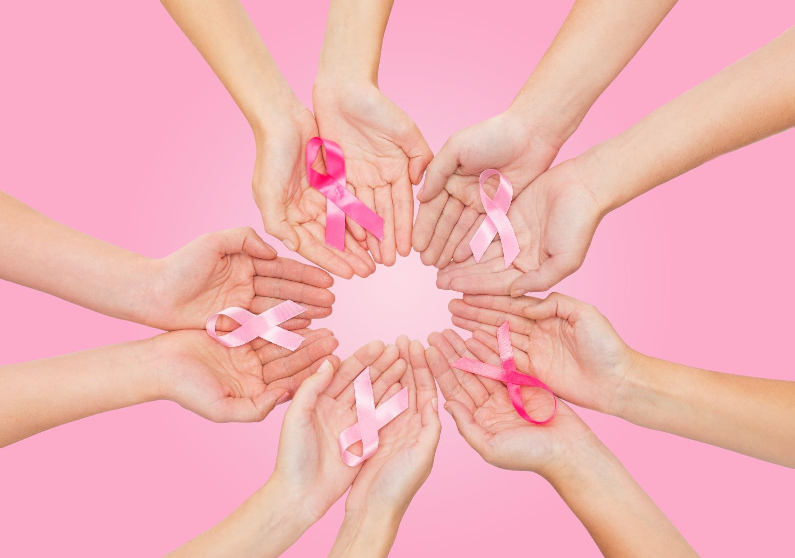 Acercamiento a manos de mujeres que sostienen listónes rosa