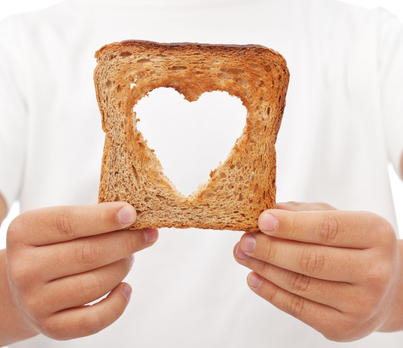 Acercamiento a las manos de un chef soteniendo un pan con recorte interno en forma de corazón