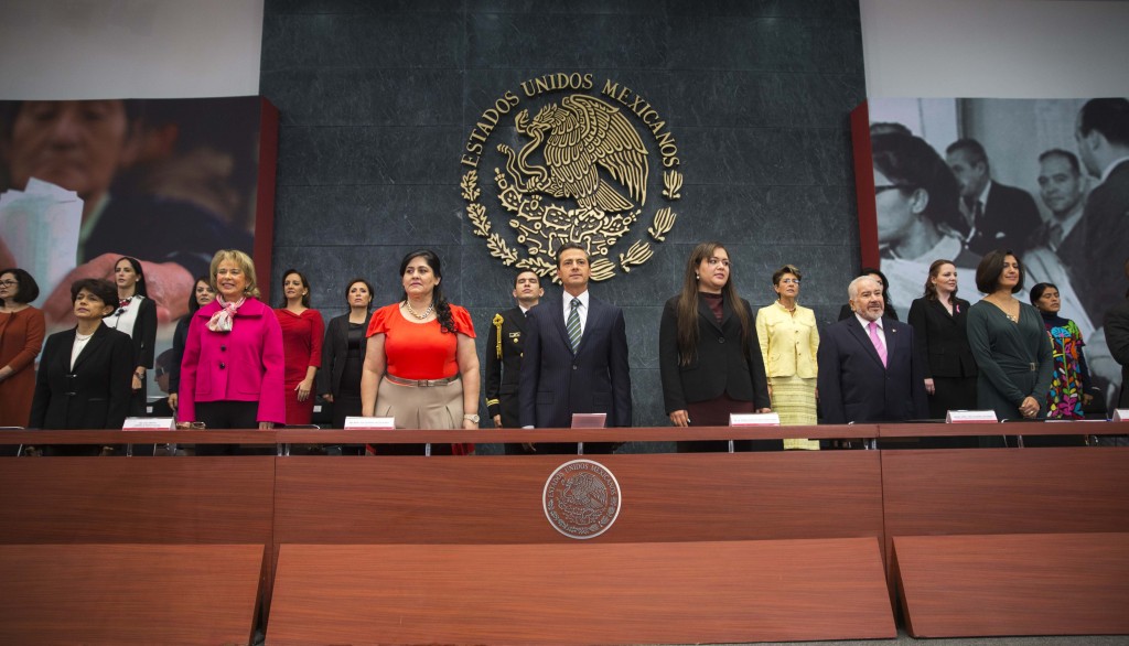 Funcionarios de pie al fondo el escudo nacional de los Estados Unidos Mexicanos