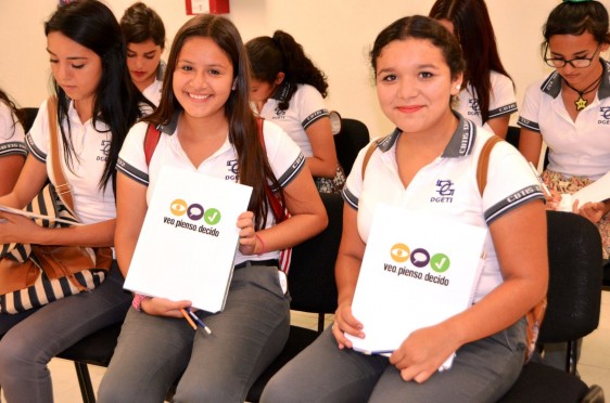 Dos adolescentes mostrando una folder con el logotipo de la campaña “Veo, Pienso, Decido”