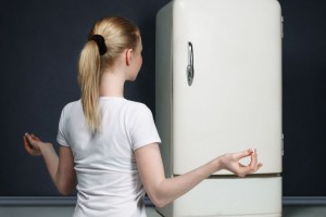 Mujer meditando enfrente de un refrigerador
