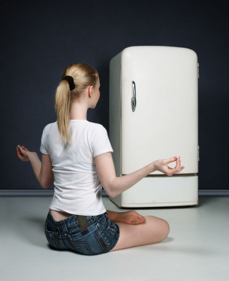 Mujer meditando enfrente de un refrigerador