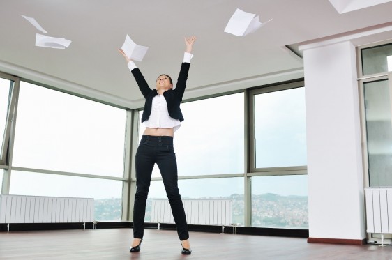 Mujer aventando papeles al aire en una oficina