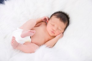 Bebé de 8 días de nacido y prematuro por 4 semanas durmiendo sobre una tela blanca