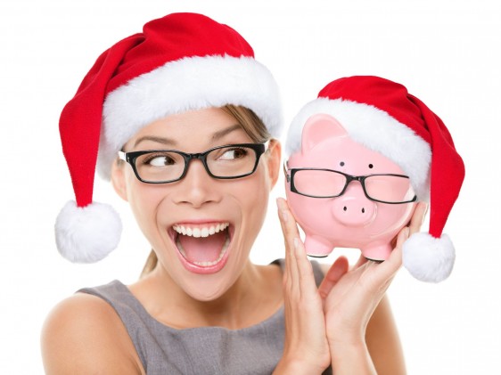 Mujer con gorro de navidad y una alcancía en forma de puerquito con sombrero navideño