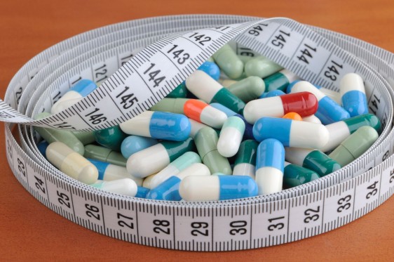 Medicamentos en píldoras rodeados por una cinta metrica