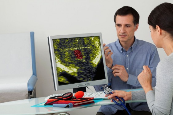 Hombre en una consulta observando con doctora una ecografía