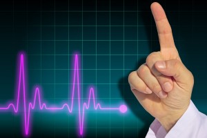Mano de medico levantando el dedo índice al fondo un electrocardigrama
