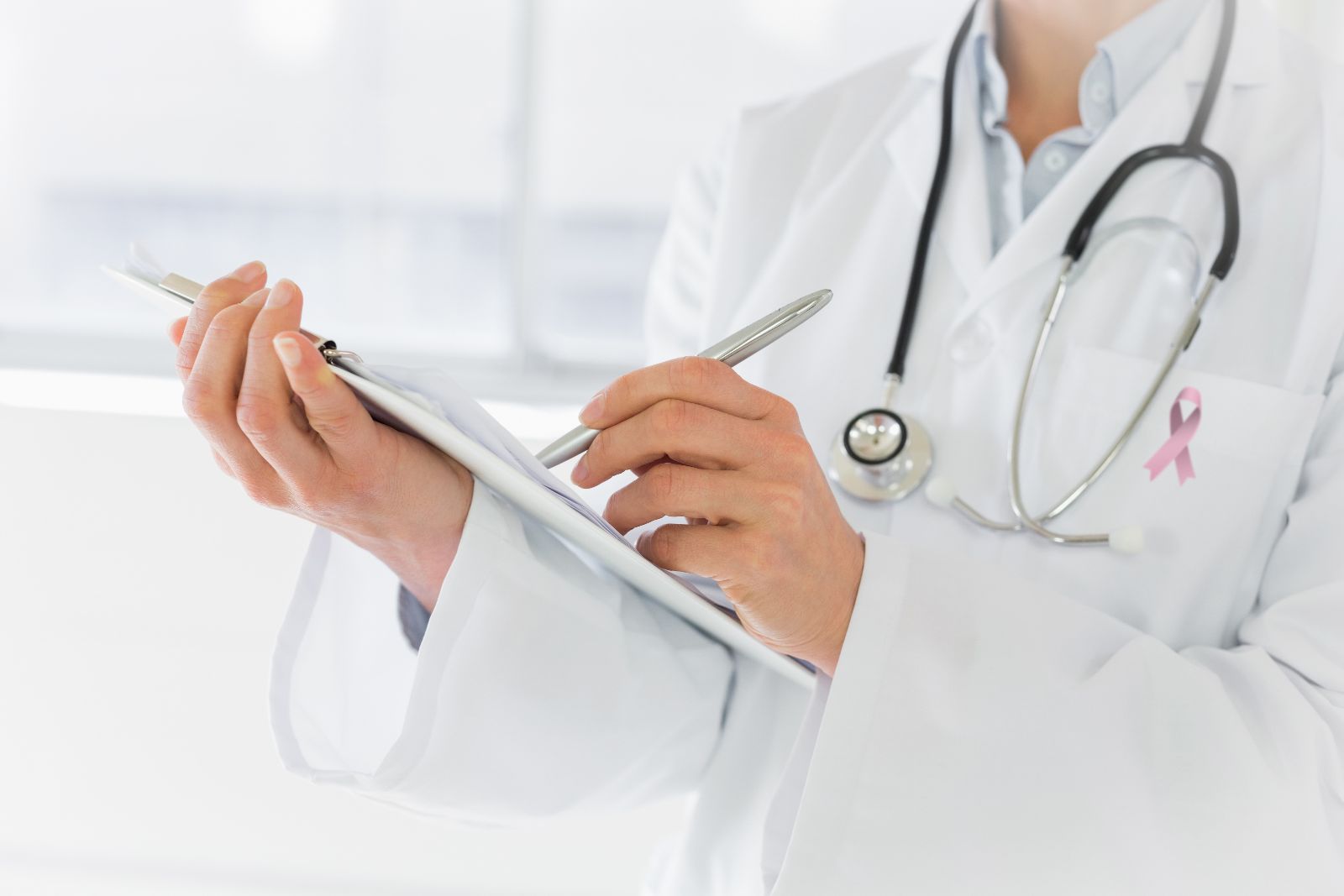 Acercamiento a una doctora que sostiene una tabla con clip escribiendo