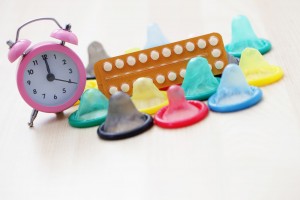 Condones y pastillas anticonceptivas con un reloj desperator