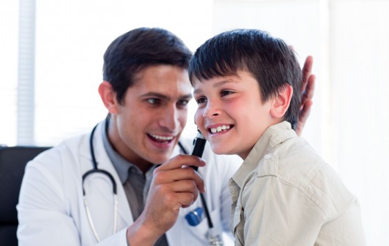 Médico usando un otoscopio para mirar el oído de un niño