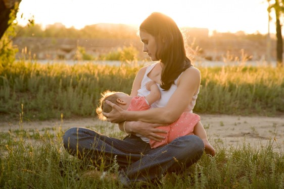 Madre amamantando a un bebé en un atardecer en el campo