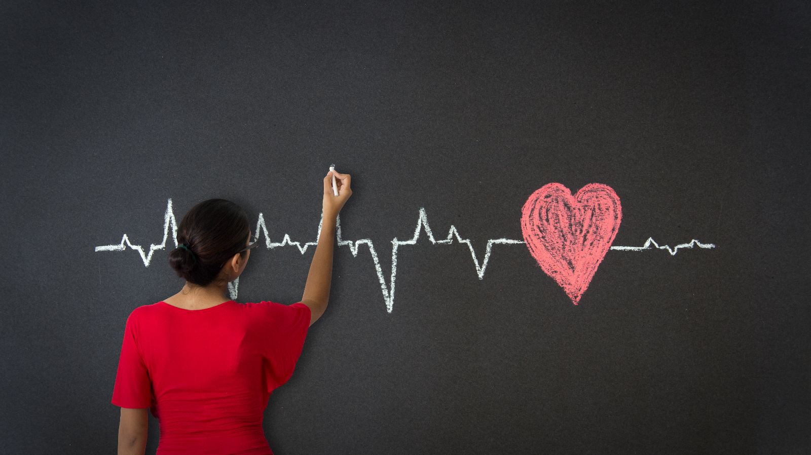 Adolescente dibujando en un pizarrón un electrocardiograma