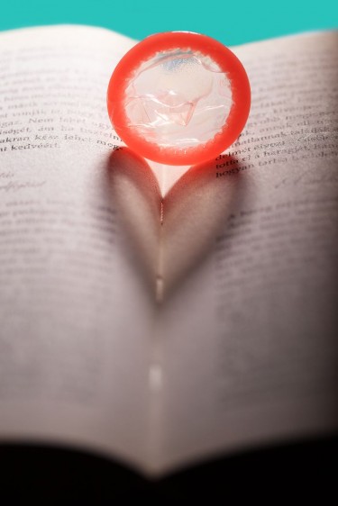 Condón que proyecta una sombra en forma de corazón en un libro