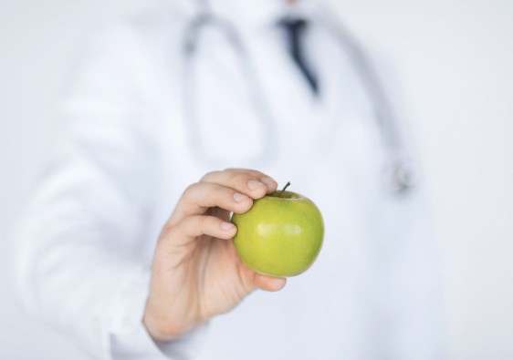 Médico mostrando una manzana verde