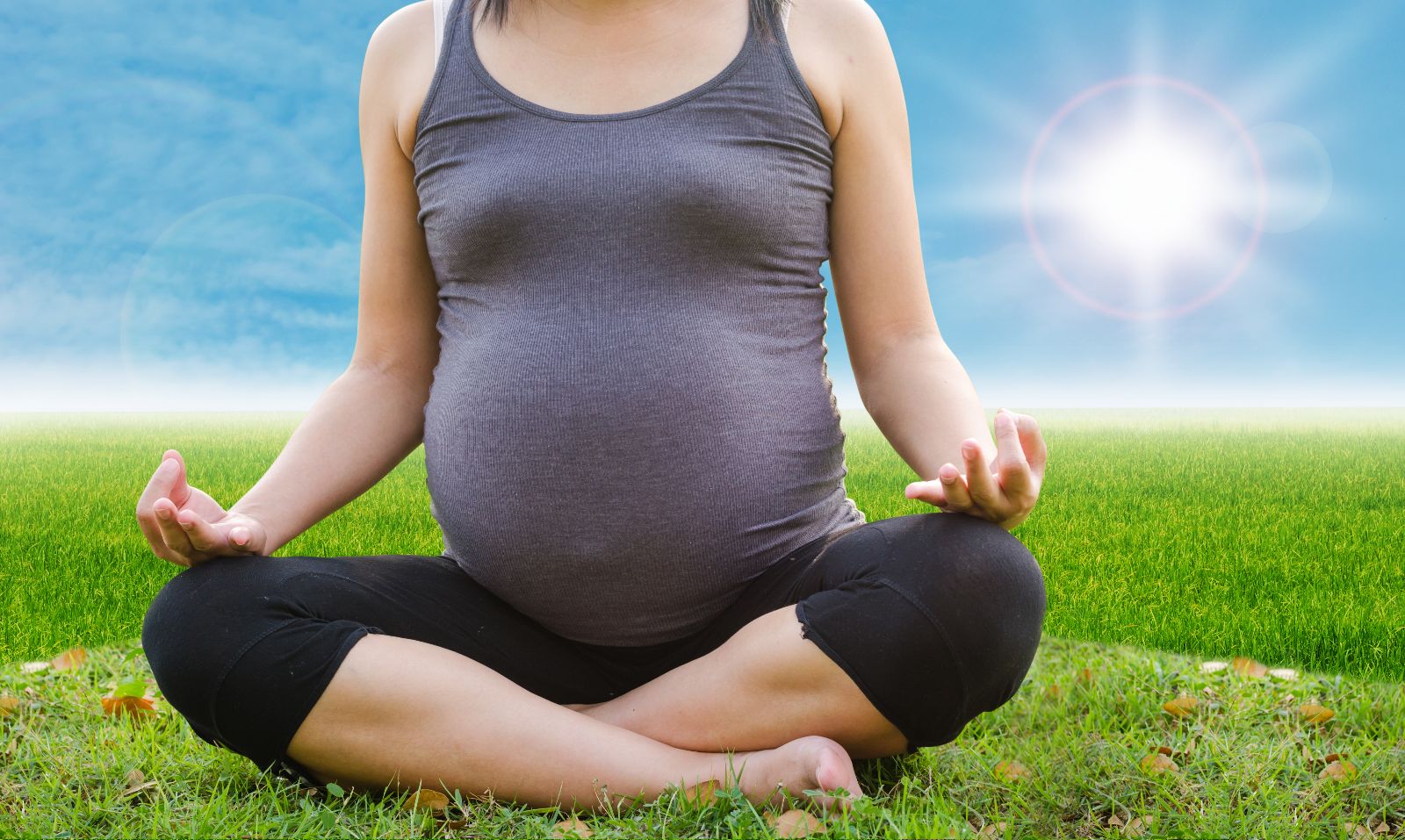 Mujer meditando en un campo verde con sol