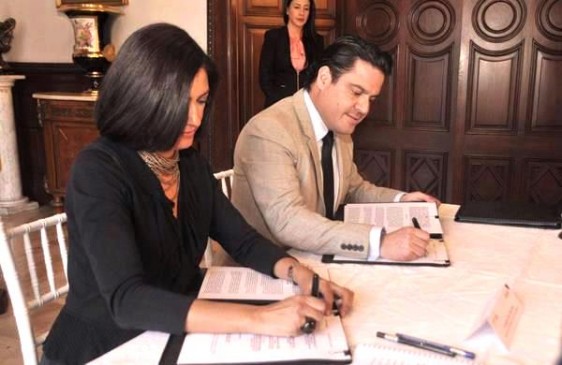 Lorena Cruz Sánchez y Aristóteles Sandoval Díaz firmando un documento