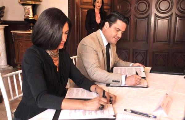 Lorena Cruz Sánchez y Aristóteles Sandoval Díaz firmando un documento