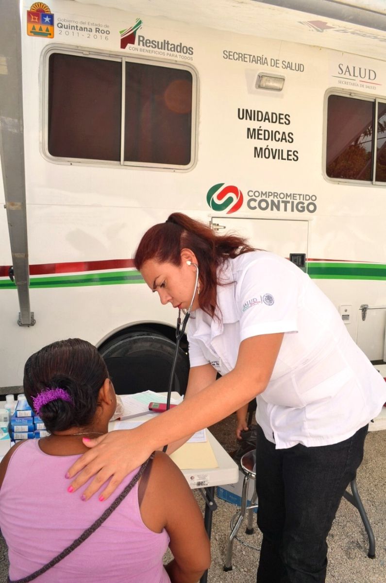 Doctora revisando a paciente enfrente de la unidad medica móvil