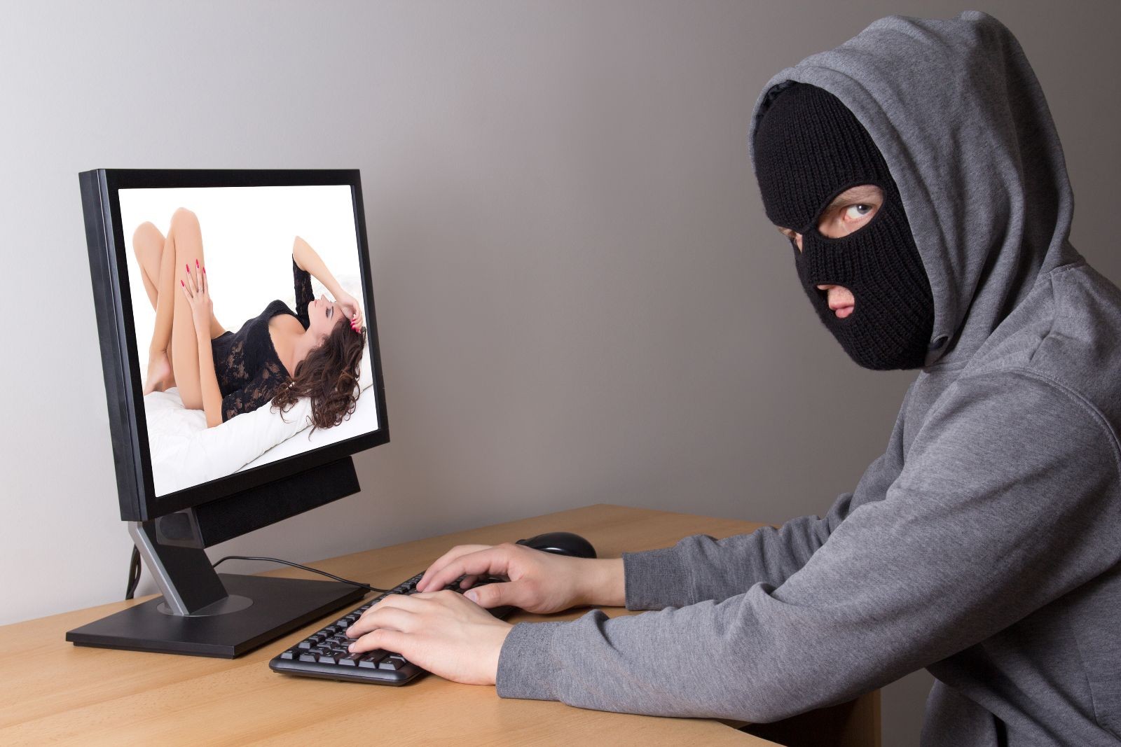 Hombre con mascara observando una pantalla de computadora con una imagen intima