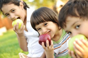 Grupo de niños comiendo manzanas en un parque