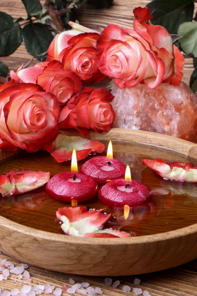 Vela con rosas en un recipiente con agua