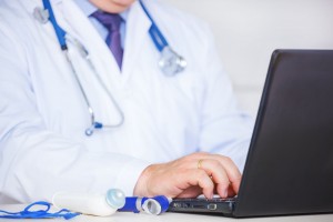 Acercamiento a las manos de un médico sentado enfrente de una computadora