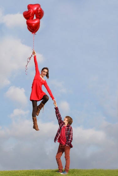 Adolescente con globos y despegando agarrada de la mano de su novio