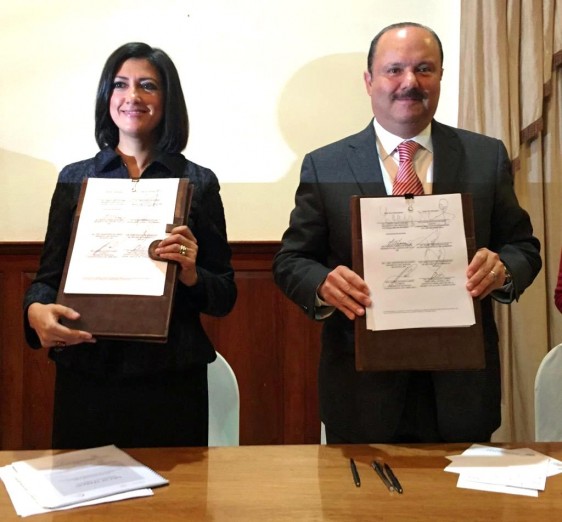 Lorena Cruz Sánchez y César Duarte Jáquez sosteniendo un documento con firmas