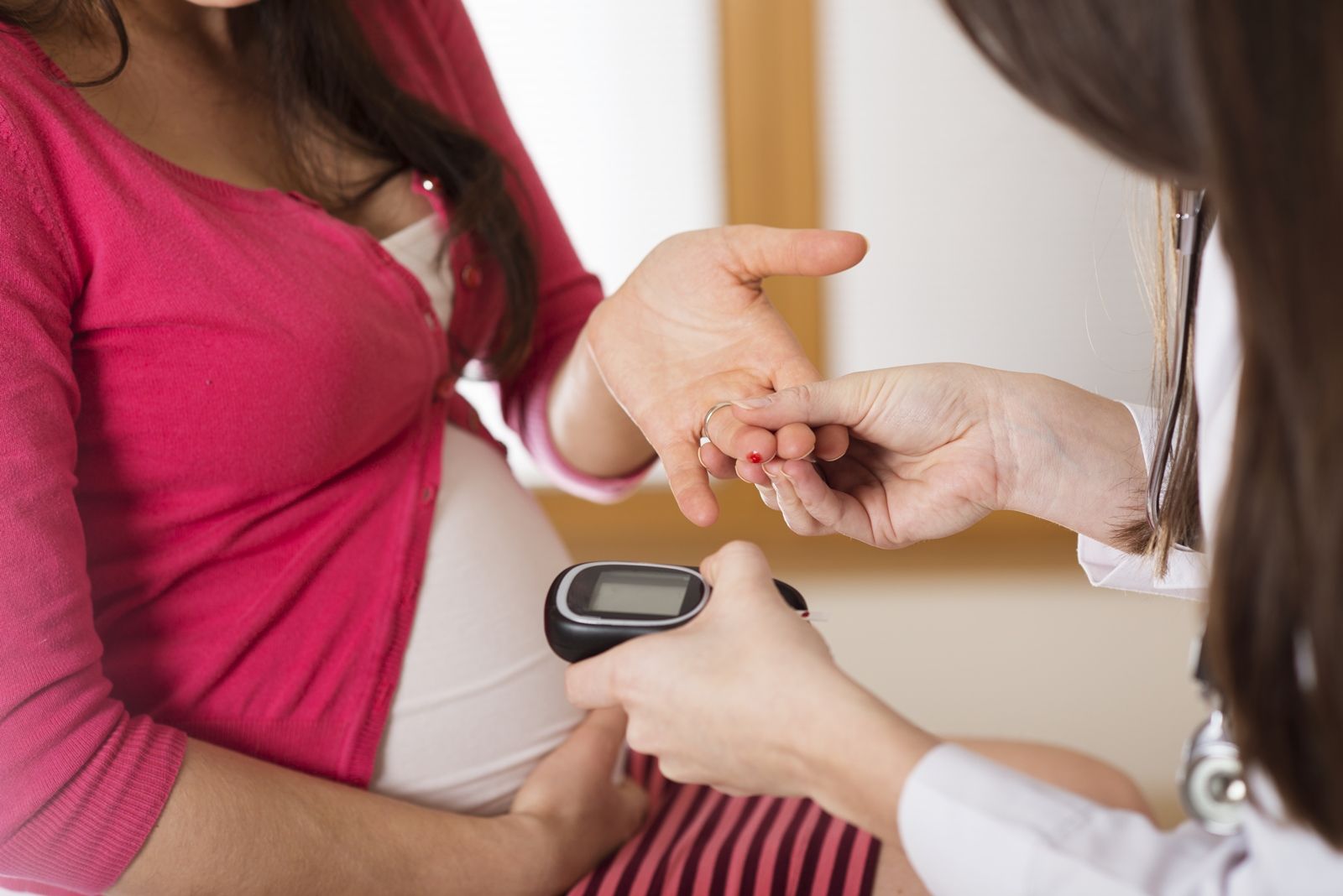 Mujer da la mano a una doctora para medir glucosa