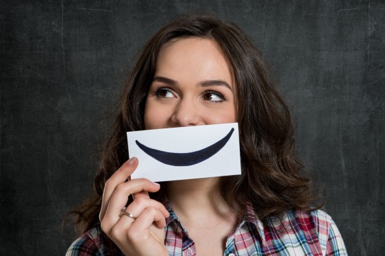 Mujer con una hoja de papel en su boca con una sonrisa