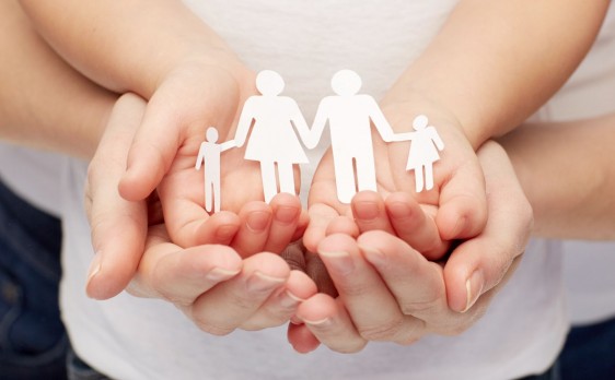 Acercamiento a las manos de una mujer y una nila que sostienen un recorte de papel con la forma de una familia
