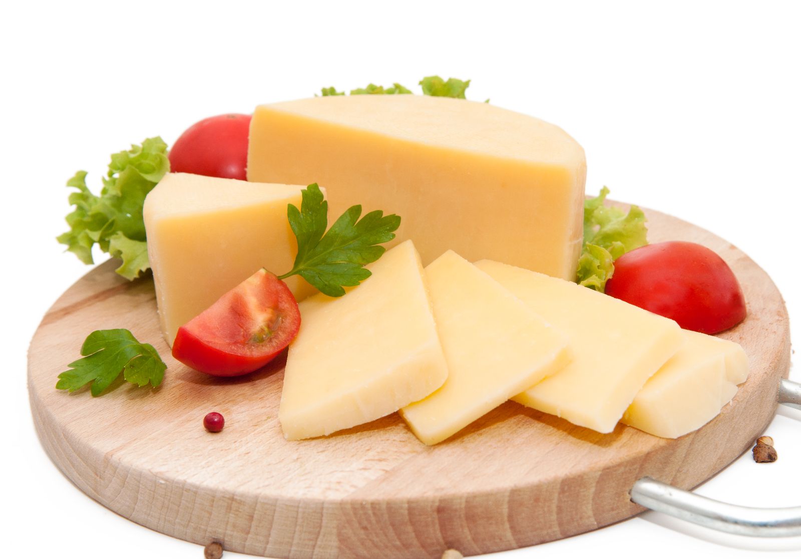 Queso con jotomates y hojas verdes en una tabla de madera