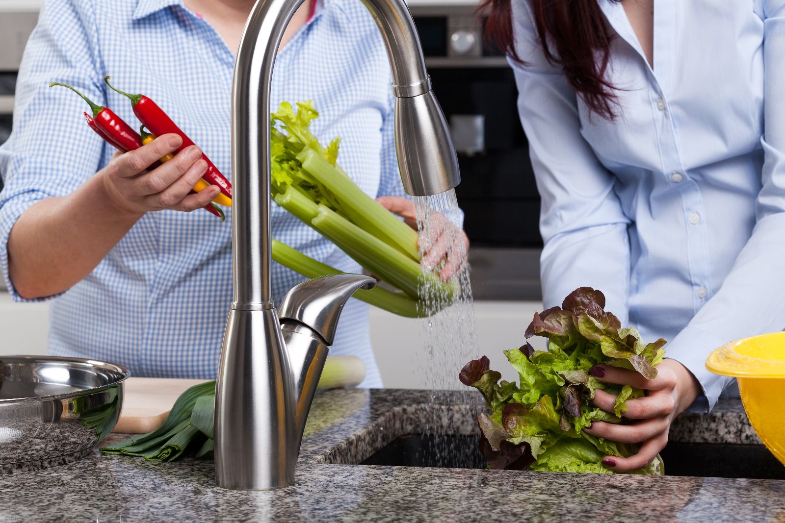 Acercamiento a las manos de un hombre y una mujer lavando verduras