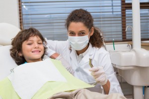 Dentista pediátrico sostiene taladro con niño en una silla