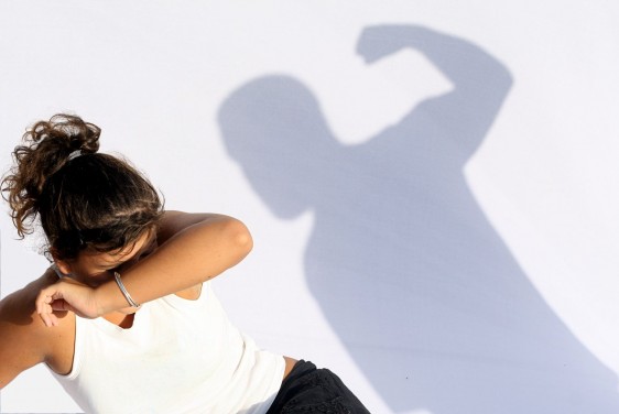 Imagen de una mujer cibriendose de una sombra para ilustrar violencia doméstica, abuso conyugal